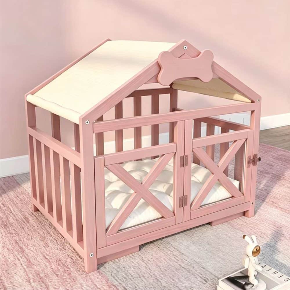 A modern, blush pink wooden pet house crate on a pink and grey rug, styled as a miniature house with a canvas roof, a soft white mattress, and open double doors.