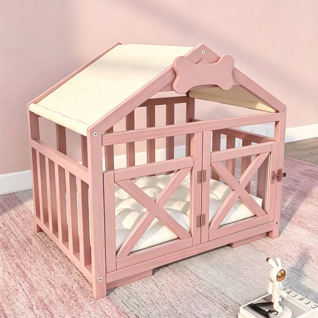 A modern, blush pink wooden indoor dog crate on a pink and grey rug, styled as a miniature house with a canvas roof, a soft white mattress, and open double doors. A modern, blush pink wooden pet house crate on a pink and grey rug, styled as a miniature house with a canvas roof, a soft white mattress, and open double doors.