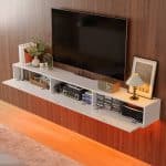 White floating TV stand with one drop-down door open, revealing storage space for electronic devices.
